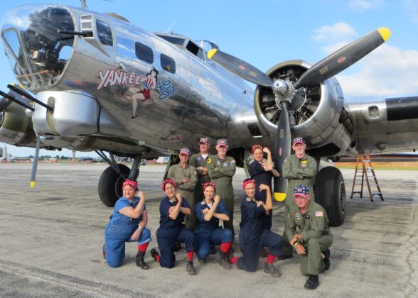 A group dressed as Rosie the Riveter in front of the Yankee Lady B-17 bomber at the Yankee Air Museum in Ann Arbor, highlighting a family-friendly historical attraction.