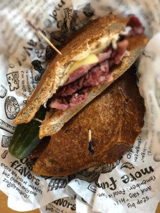 A signature sandwich with a pickle from Zingerman&rsquo;s Deli in Ann Arbor, a family-friendly spot known for its famous food and welcoming ambiance.