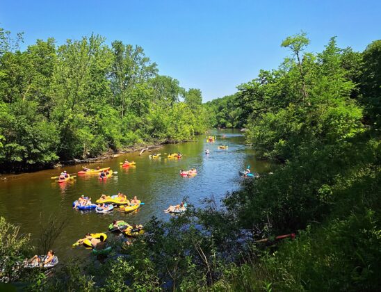 Families enjoying a sunny day tubing and kayaking on the Huron River in Ann Arbor, a popular family-friendly outdoor activity.