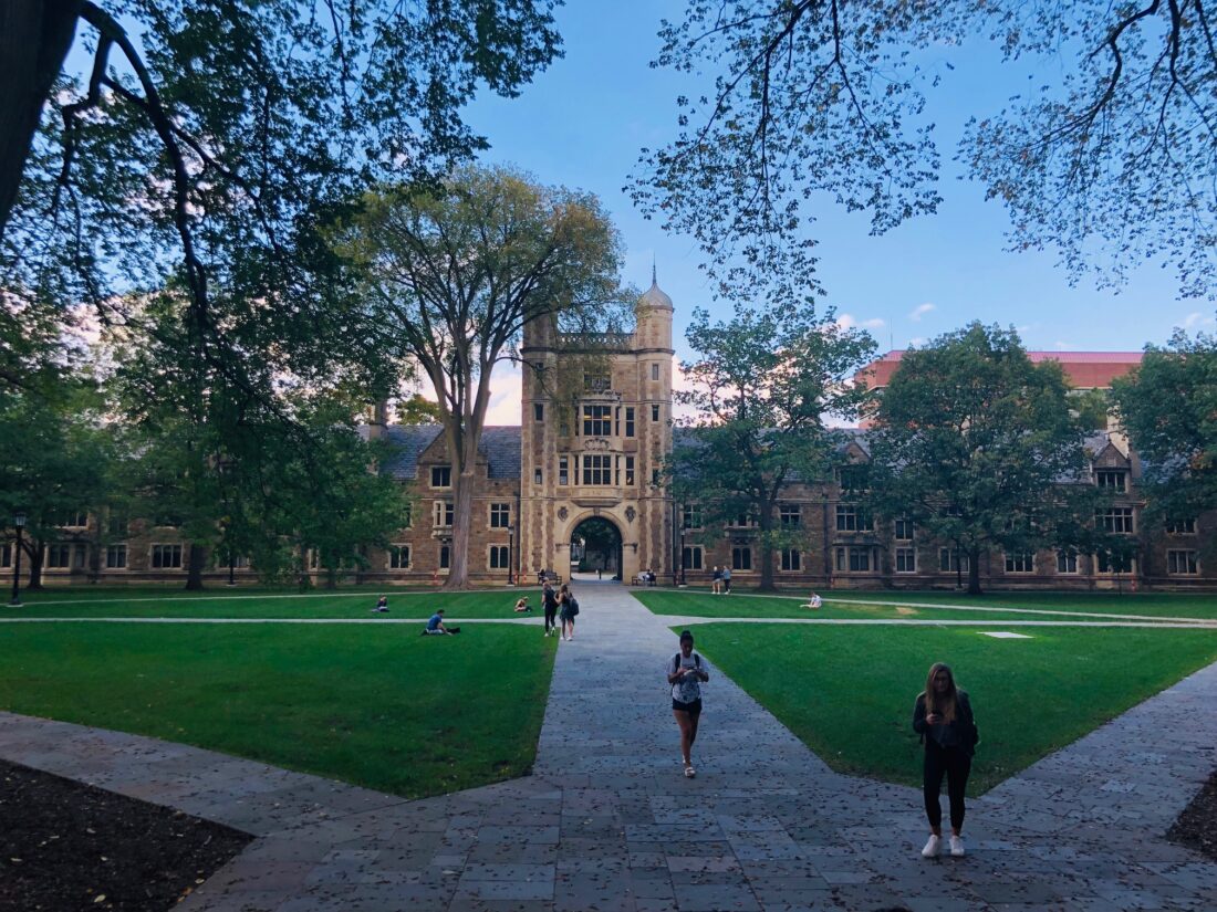 The picturesque University of Michigan Law Quad, featuring historic gothic architecture, lush green lawns, and students relaxing, making it a family-friendly area for a campus stroll.