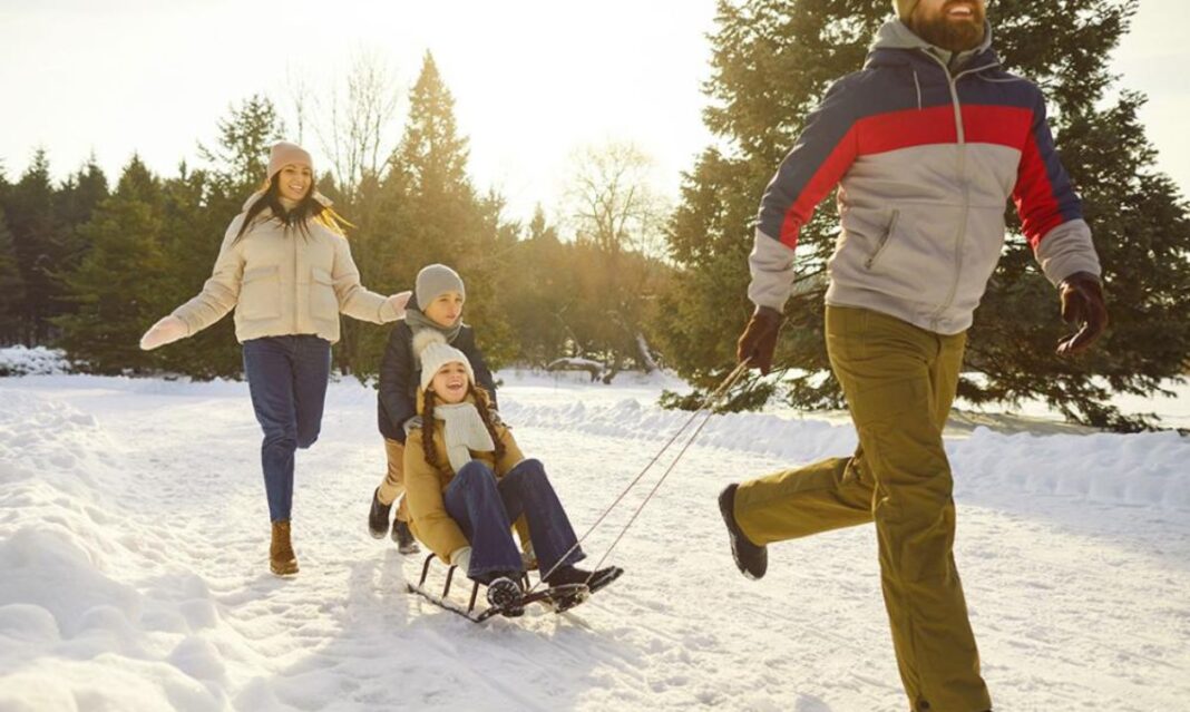 A family enjoying an outdoor sledding activity in the snow, showcasing a fun way to stay active and fit during the holidays.