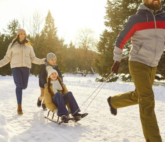 Winter Sports at the DNR Outdoor Adventure Center A family enjoying an outdoor sledding activity in the snow, showcasing a fun way to stay active and fit during the holidays.