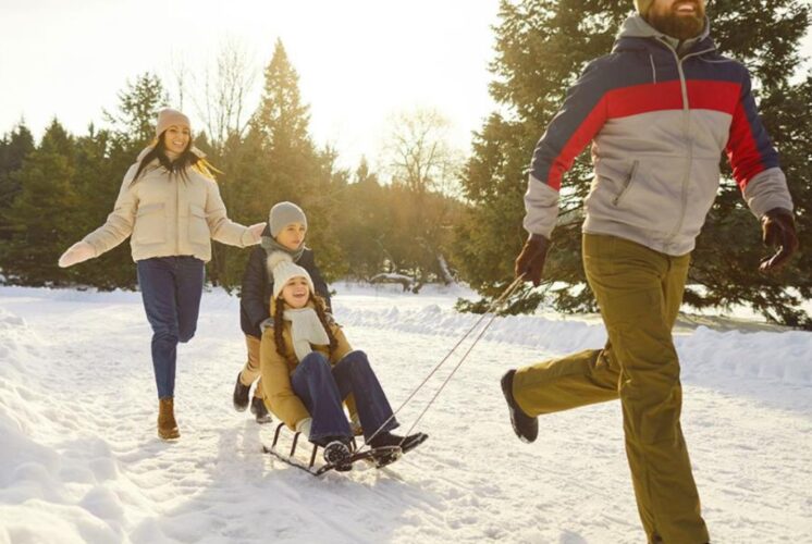 A family enjoying an outdoor sledding activity in the snow, showcasing a fun way to stay active and fit during the holidays.