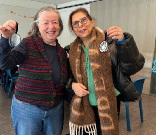 Two participants smile and hold completed crafts at the Winter Solstice Celebration Cranbrook showing hands on seasonal creativity in the art space