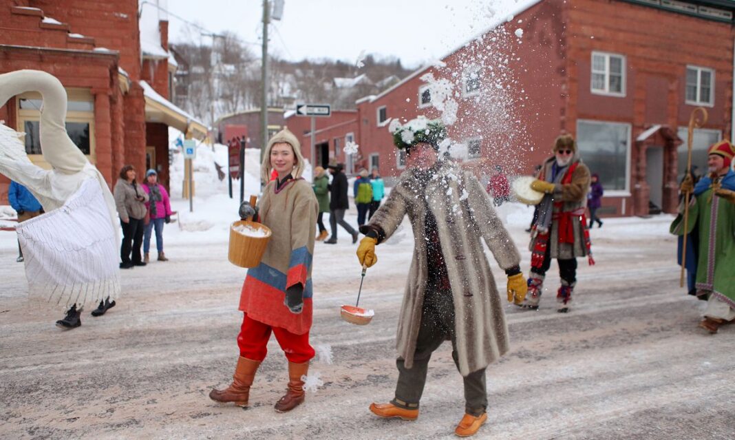 Participants in traditional Finnish attire celebrate during the Heikinpäivä Festival parade, showcasing cultural customs with winter-themed activities in a snowy small-town setting.