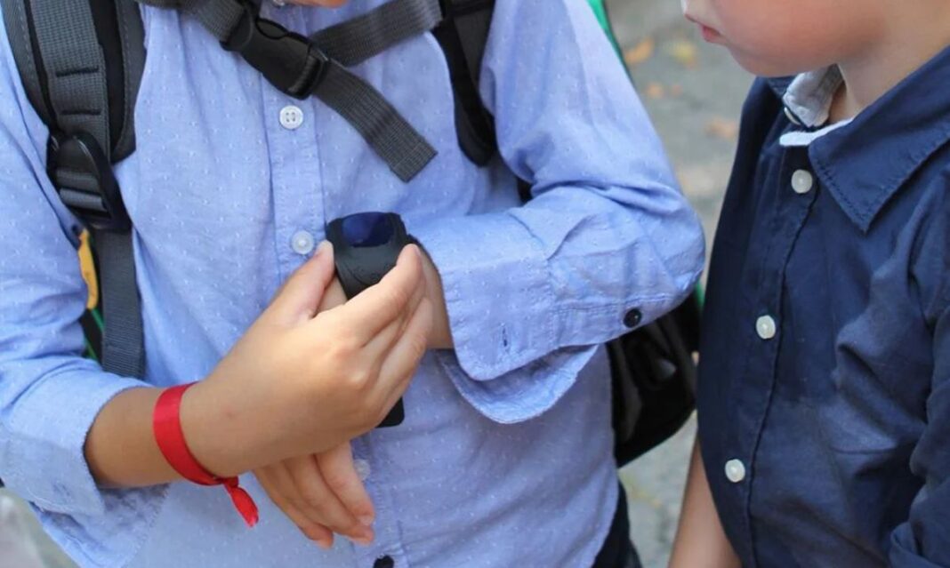 Children interacting with a small digital device, illustrating concerns about parents monitoring kids' online activities.