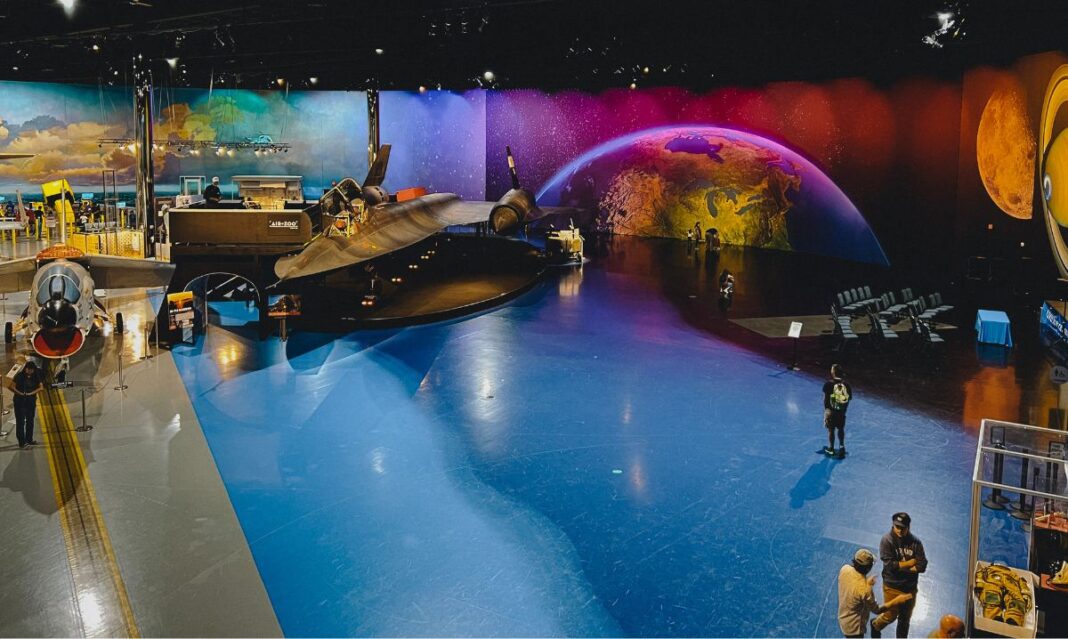The Air Zoo Aerospace & Science Museum in Kalamazoo, Michigan, featuring historic aircraft, including a black SR-71 Blackbird, set against a colorful space-themed backdrop.