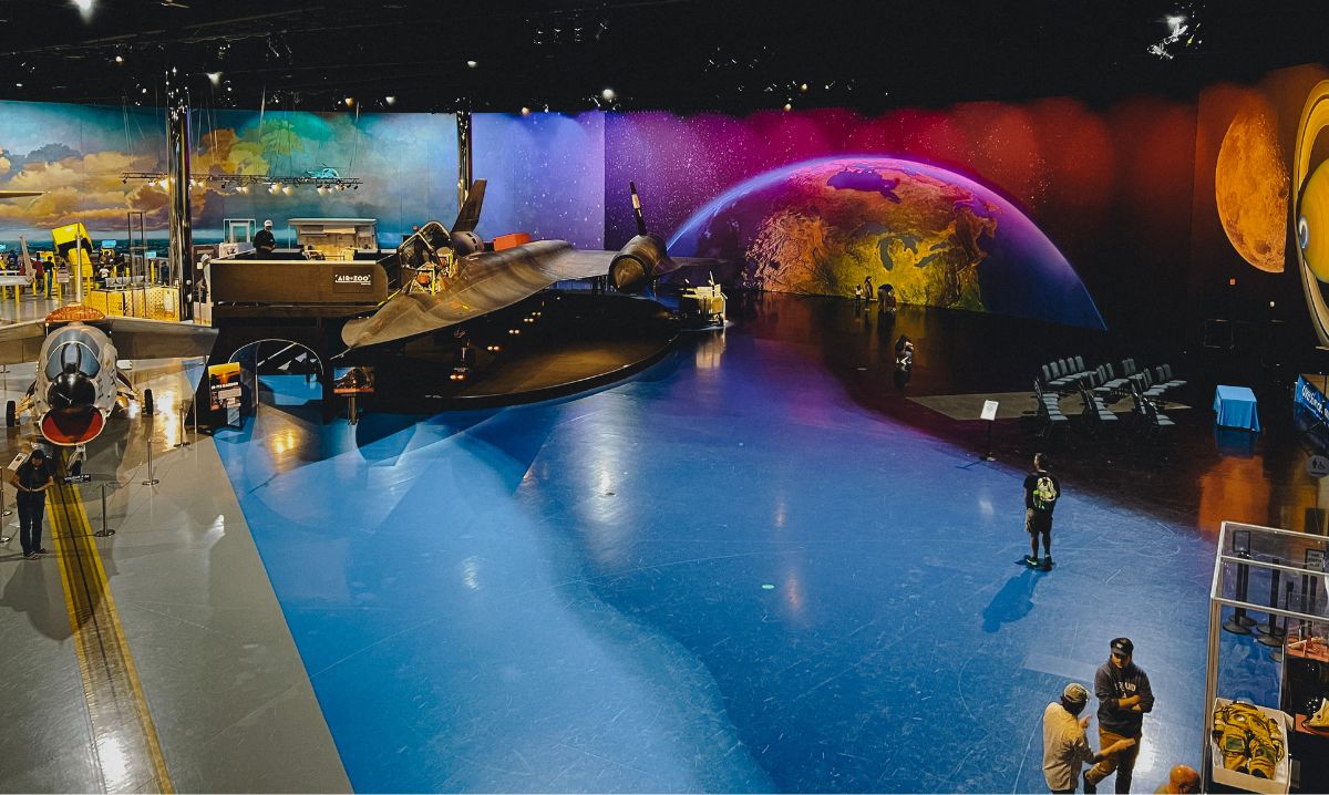 The Air Zoo Aerospace & Science Museum in Kalamazoo, Michigan, featuring historic aircraft, including a black SR-71 Blackbird, set against a colorful space-themed backdrop.