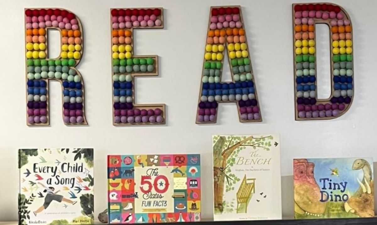 Colorful "READ" display with rainbow decorations and children’s books, including "Every Child a Song" and "Tiny Dino," showcased at Fine Print Bookshop in Metro Detroit.