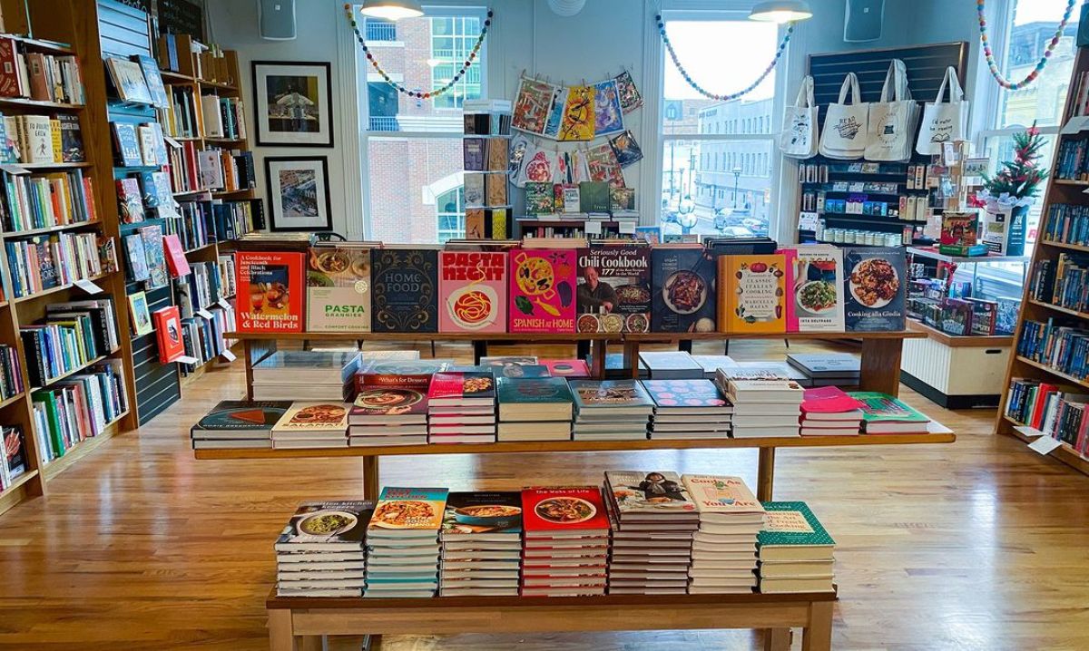 Bright and inviting interior of Literati Bookstore, featuring colorful cookbooks and a wide selection of books displayed on wooden shelves and tables.