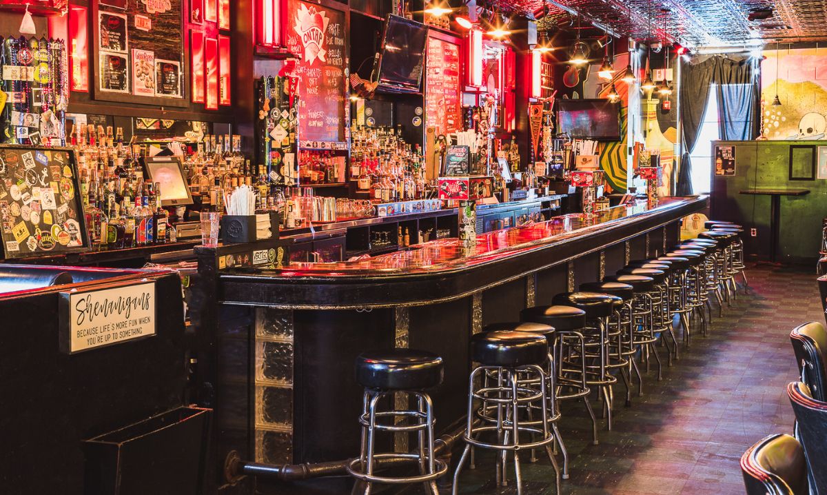 Stella’s Lounge in Grand Rapids, Michigan, featuring a retro-style bar with a long counter, vintage decor, neon lighting, and a wide selection of drinks.