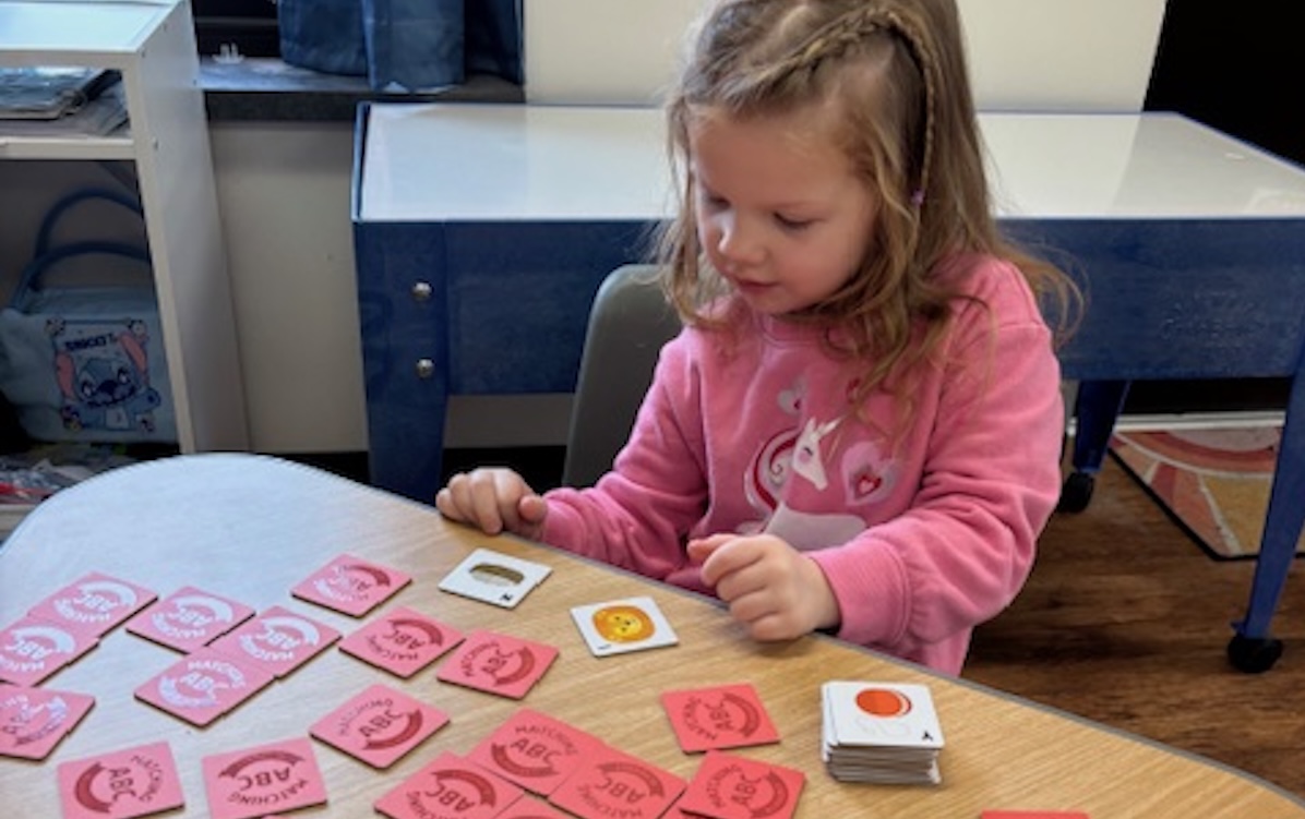 Preschool student at an elementary school in Romulus practicing early literacy and problem-solving skills with a matching card game.