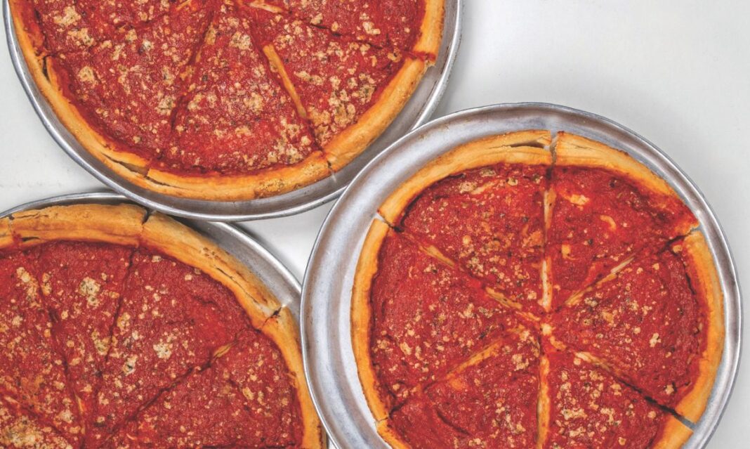 Three deep-dish pizzas with rich tomato sauce and cheese, served on metal trays at a kid-friendly restaurant in Downtown Detroit.