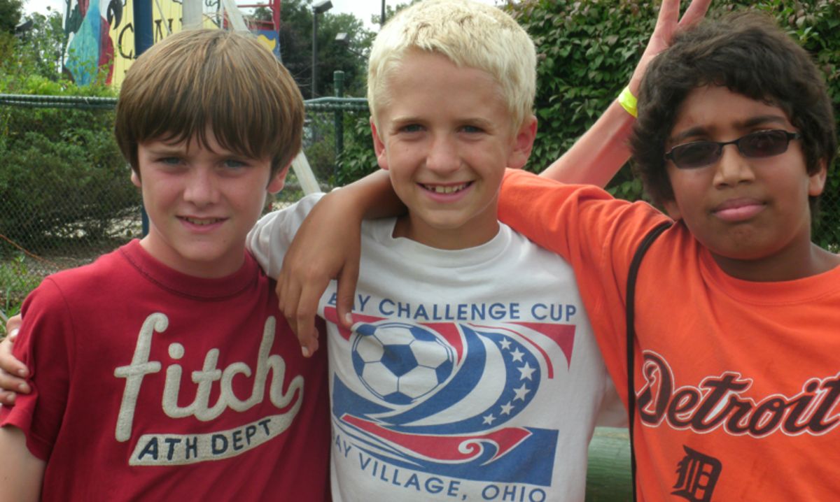 Three boys smile and pose together at Camp Mirage in Michigan, showcasing the strong friendships built during summer camp. The fun and engaging environment fosters teamwork, outdoor adventures, and lifelong memories.