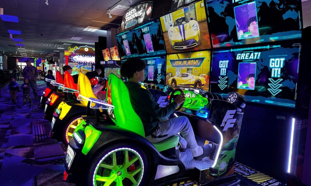 Kids enjoy an exciting arcade racing game at a Lansing recreation center, a fun spring break destination for families.