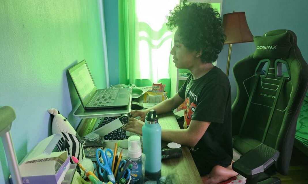 Middle school student attending online public school in Michigan, working on a laptop from home at a desk setup with school supplies and a gaming chair.