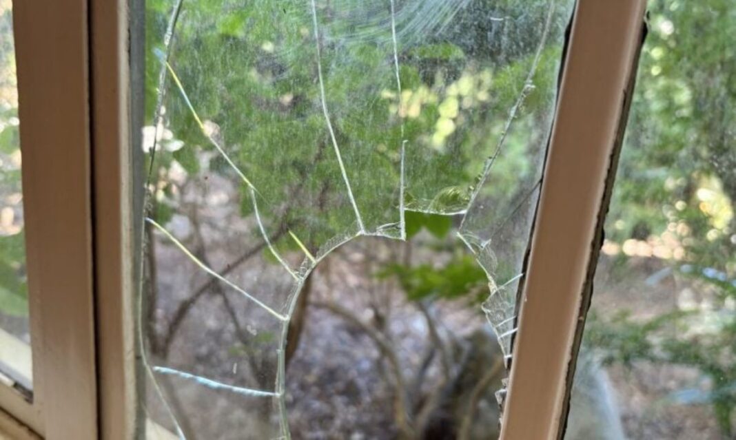 Close-up of a broken window in a house, highlighting the importance of choosing a security system for home protection.