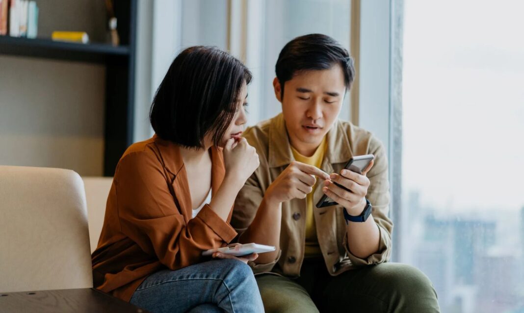 Man and woman looking at a smartphone, discussing how to cancel subscriptions.