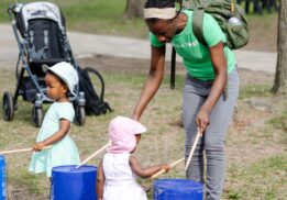 Young children and parent enjoying a hands-on drumming activity at GreenFest at the Detroit Zoo, a family-friendly outdoor spring event
