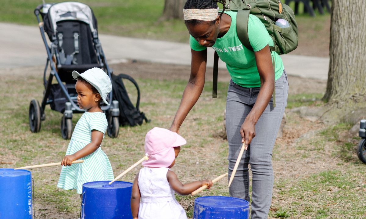 Young children and parent enjoying a hands-on drumming activity at GreenFest at the Detroit Zoo, a family-friendly outdoor spring event