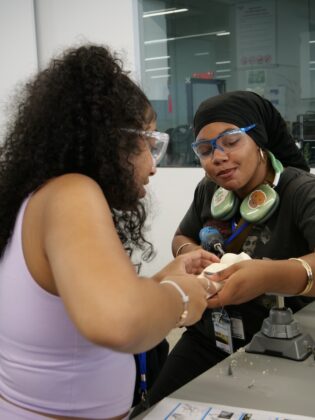 Two students engage in a hands-on design and engineering project at Lawrence Tech summer programs, working together with safety goggles and tools in a collaborative lab environment.