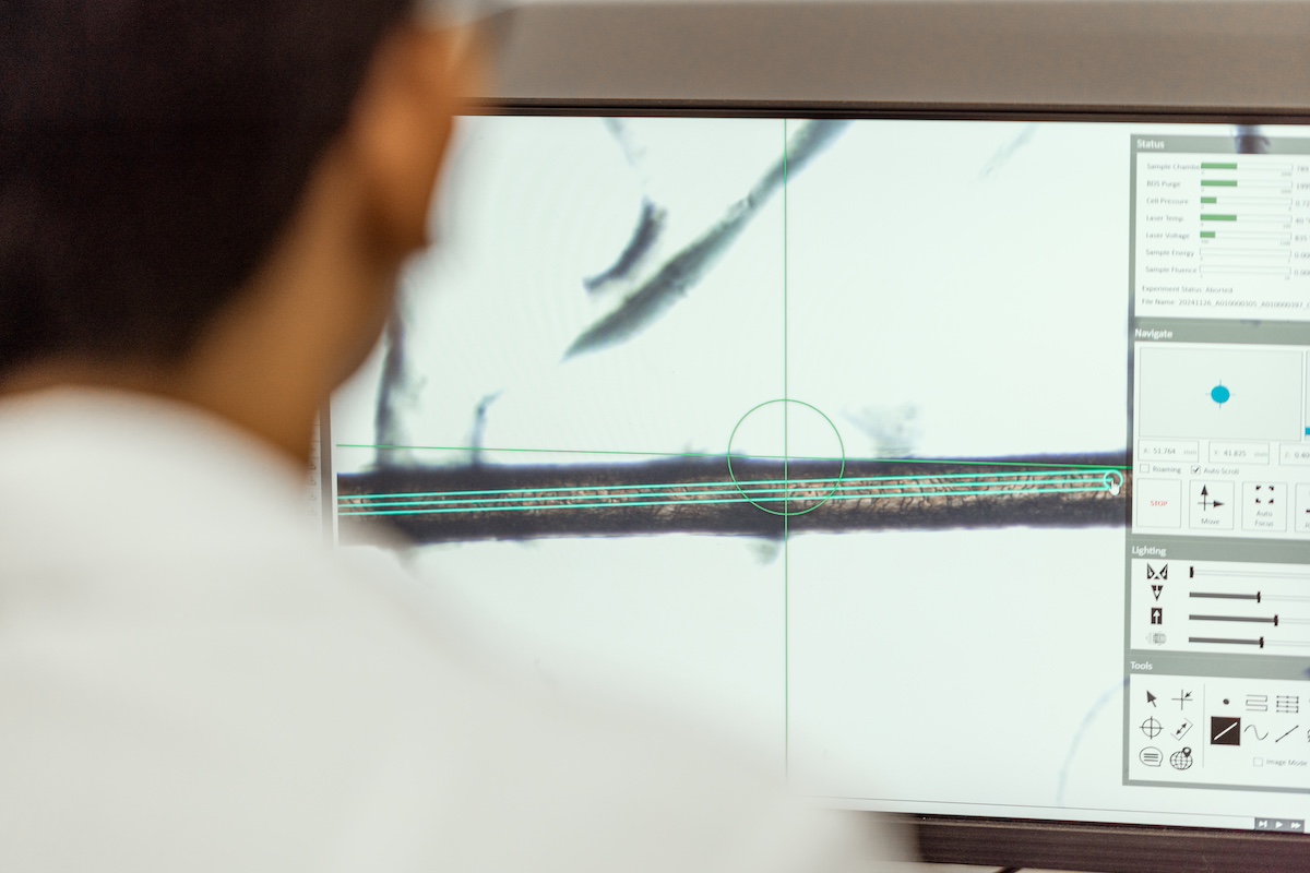 Scientist analyzing a magnified hair sample on screen using LinusBio ClearStrand ASD lab technology for autism spectrum disorder research.