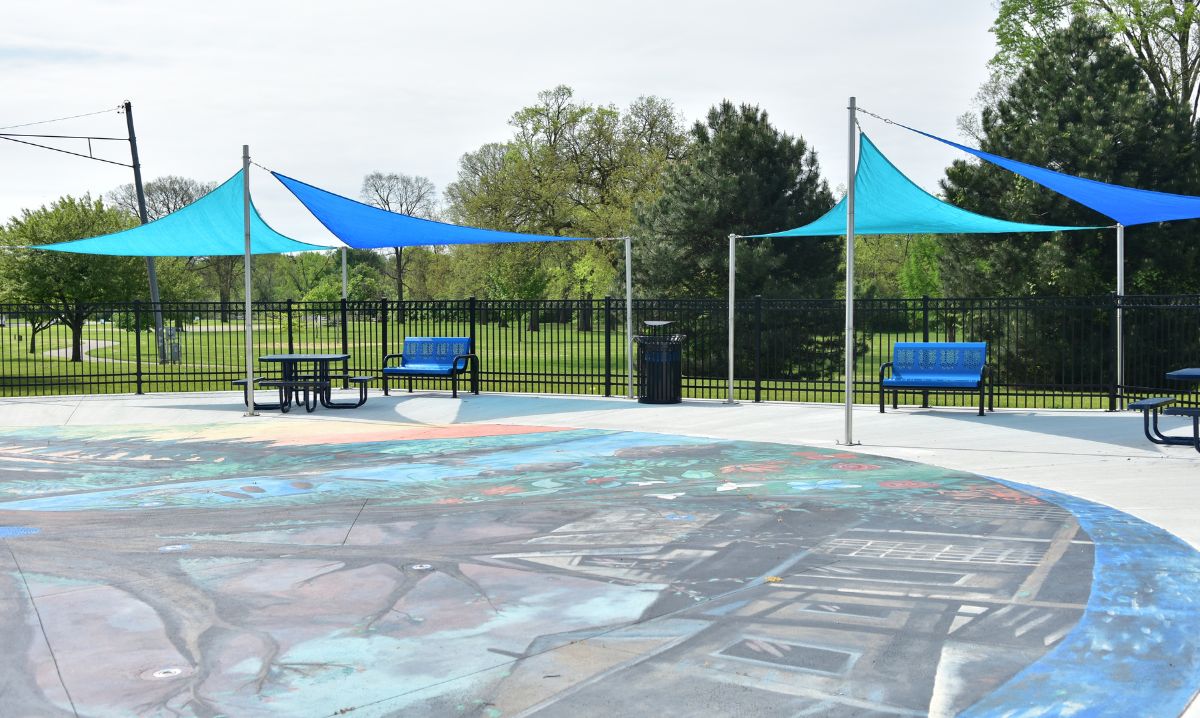 Cascade in the Shade splash pad in Mount Clemens with shaded seating, colorful pavement art, and nearby greenery—an inviting splash pad near Detroit for families.