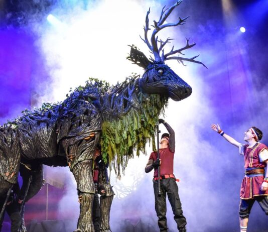 Performers interacting with a towering forest creature puppet during the Dragons & Mythical Beasts live show, a magical theater experience for families and kids