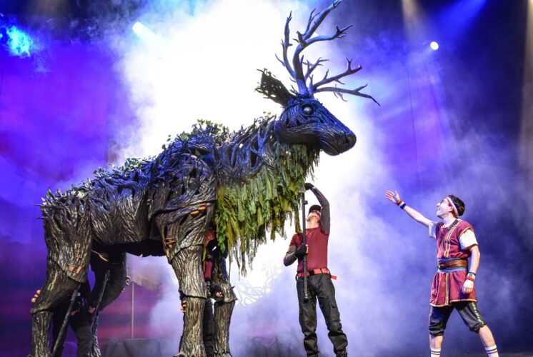 Performers interacting with a towering forest creature puppet during the Dragons & Mythical Beasts live show, a magical theater experience for families and kids