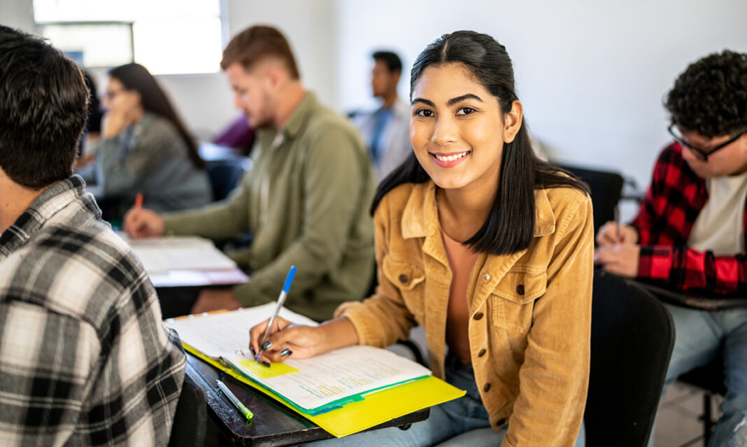 Smiling student in a college classroom, representing a teen enrolled in a fast track college program