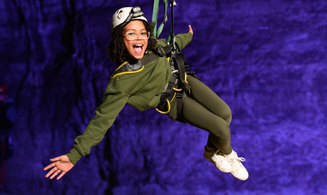 Smiling child on an indoor zipline experience, part of Louisville Kentucky family adventures.