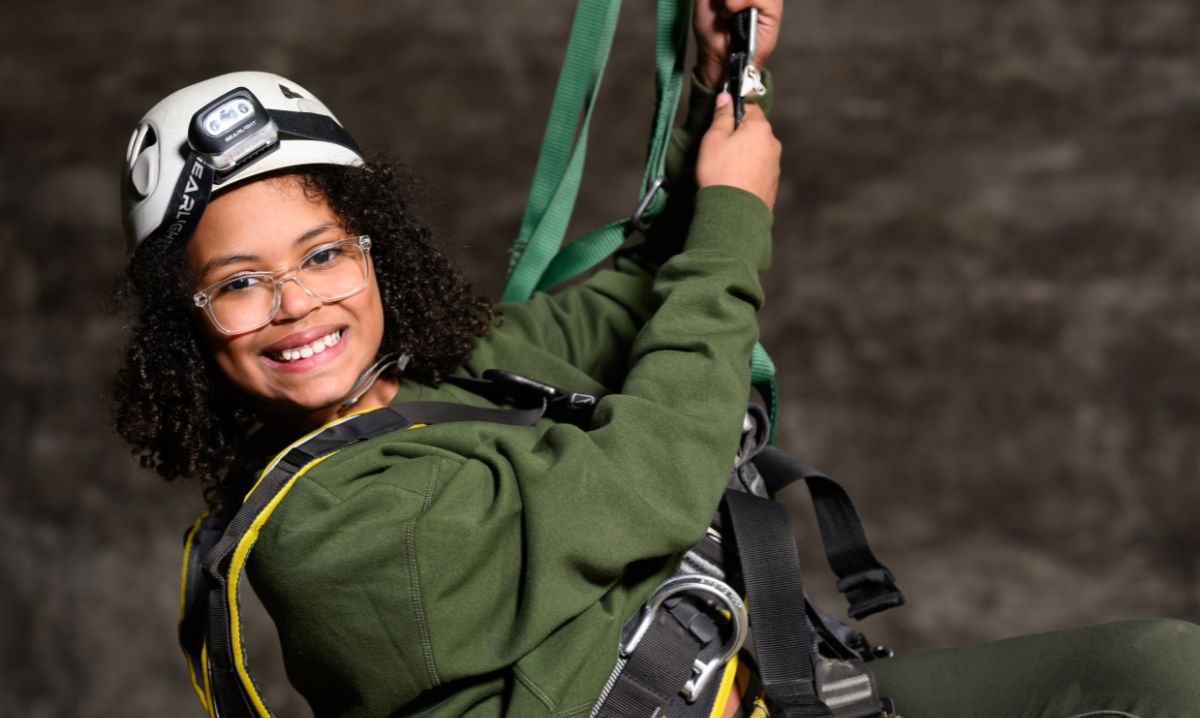 Smiling child wearing a helmet and harness ready for a zipline ride, enjoying a thrilling moment on a family adventure travel road trip.