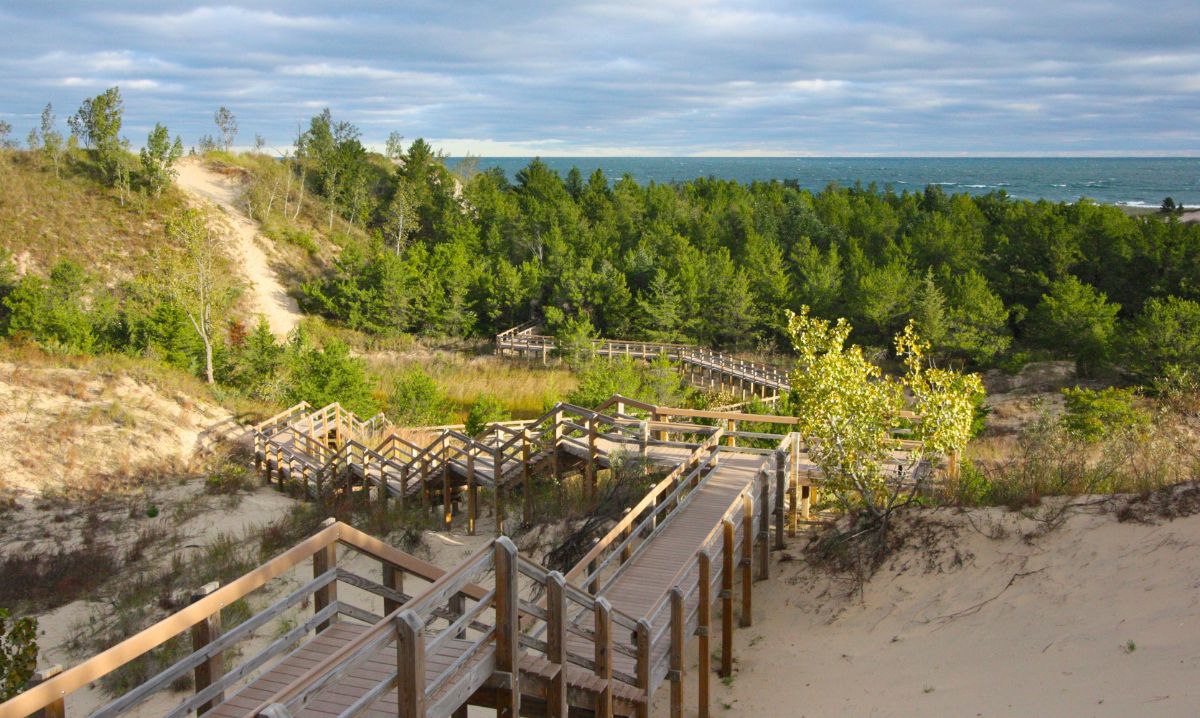 Scenic wooden boardwalk through sand dunes and forest along Lake Michigan, perfect for a family adventure travel road trip hike.