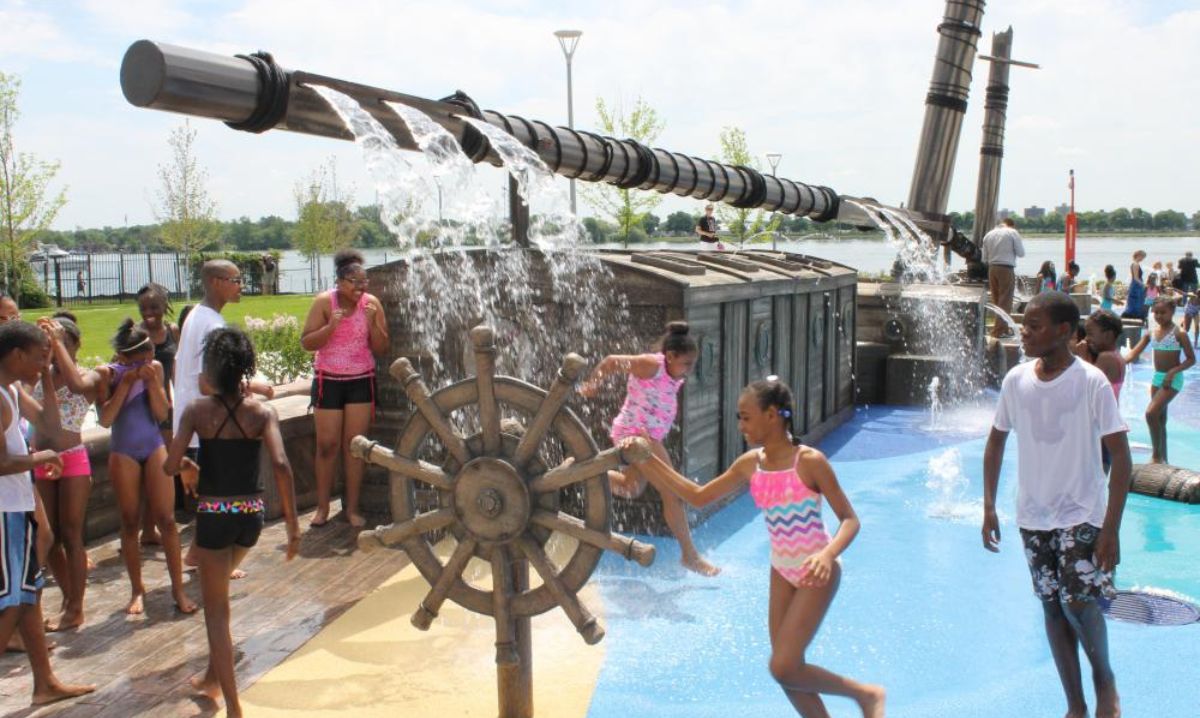 Kids playing at Mt. Elliott Park Splash Pad on the Detroit Riverfront, one of the best splash pads in Detroit for summer water fun.