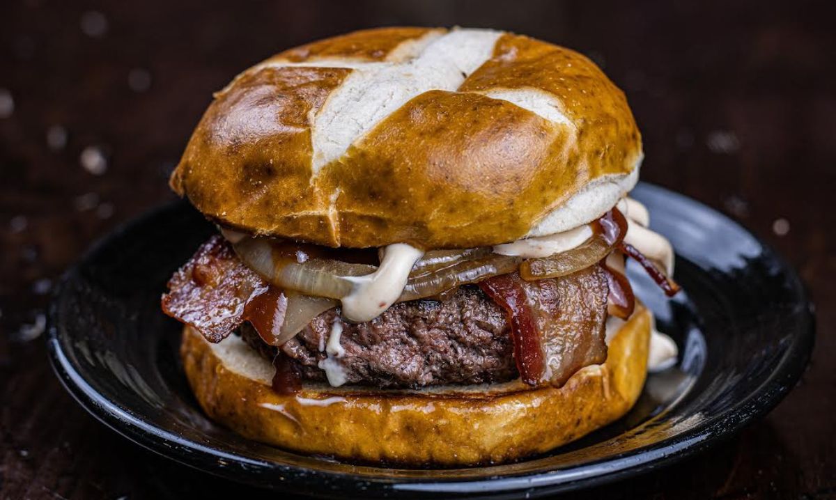 Juicy bacon cheeseburger on a pretzel bun served at a local diner, a delicious stop on a family adventure travel road trip.