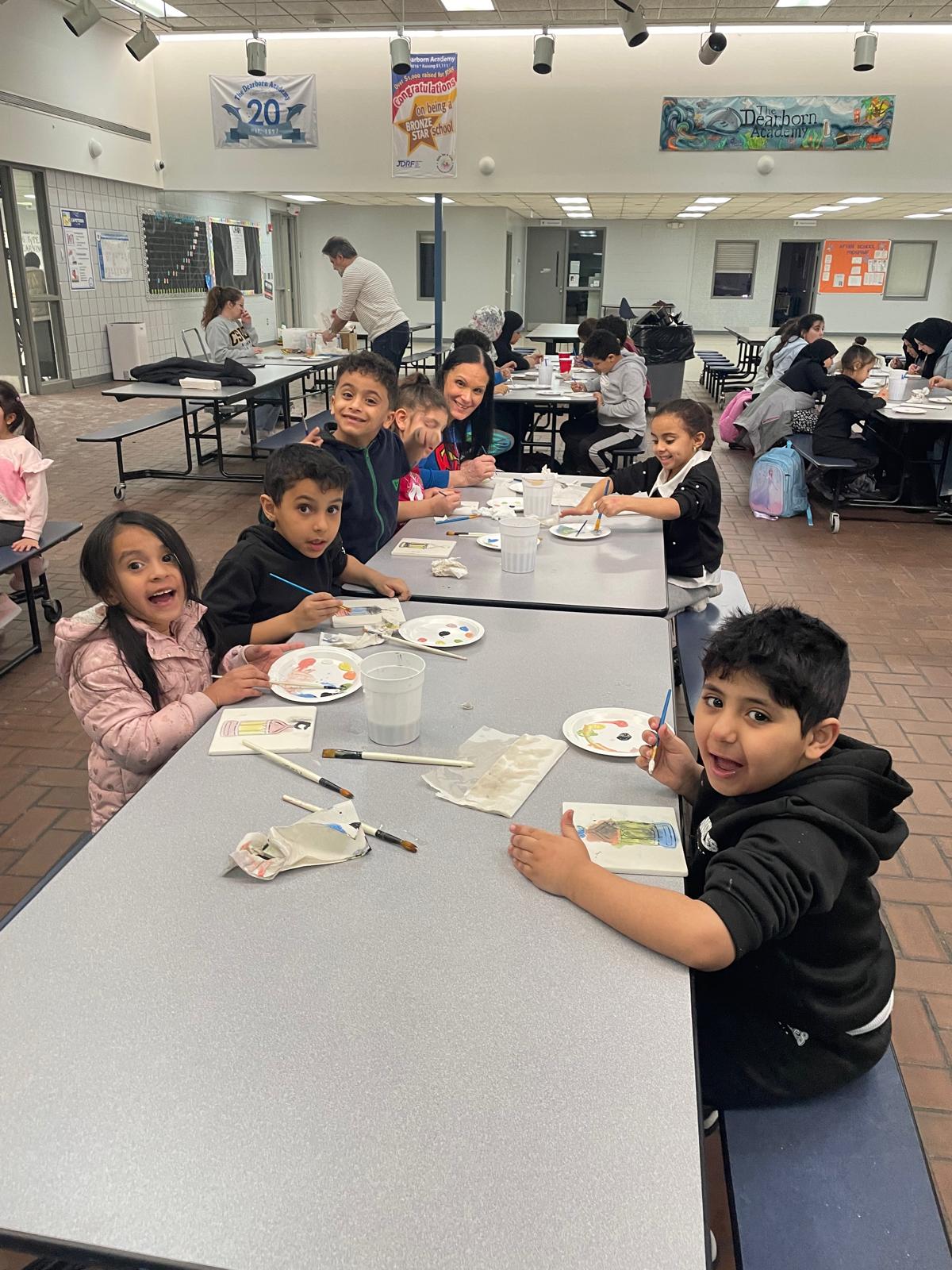Smiling students at The Dearborn Academy participating in an after-school painting activity at a Michigan charter school.