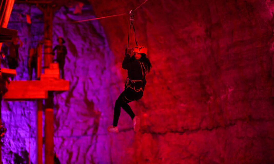 Child ziplining through a glowing underground cave during a thrilling family adventure travel road trip experience.