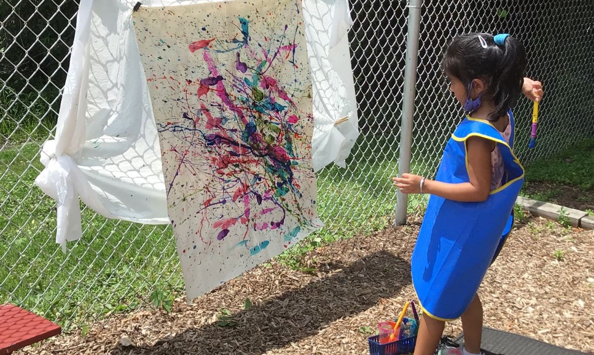 Young child painting outdoors at Novi Northville Montessori Center, one of the best metro Detroit schools for hands-on early education.