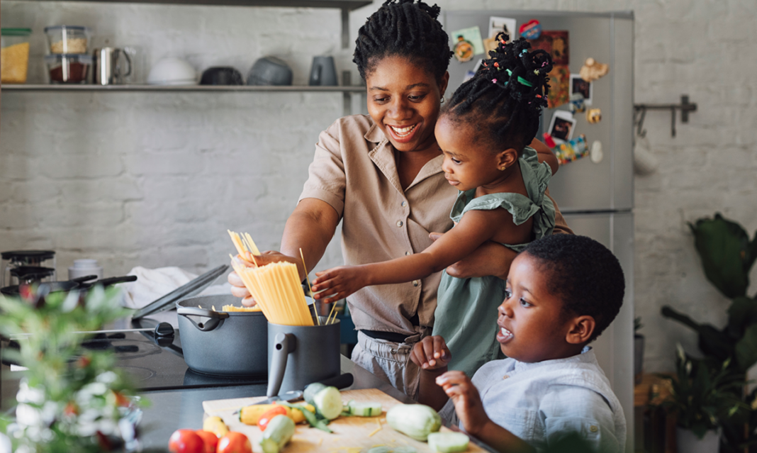 Mother helping her children prepare a meal, illustrating daily routines and autism parenting tips that support connection and skill building.