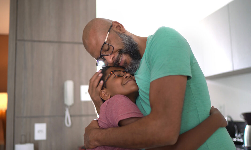 A parent and child share a calming hug in a kitchen, illustrating emotional connection and support after an emotional trigger.