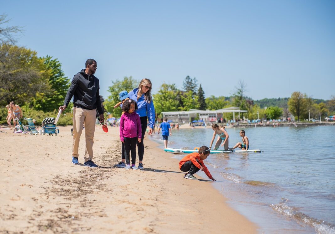 Families enjoying a sunny day at Clinch Park Beach in Traverse City, Michigan — a top family-friendly destination with water activities, sandy shores, and scenic lake views.