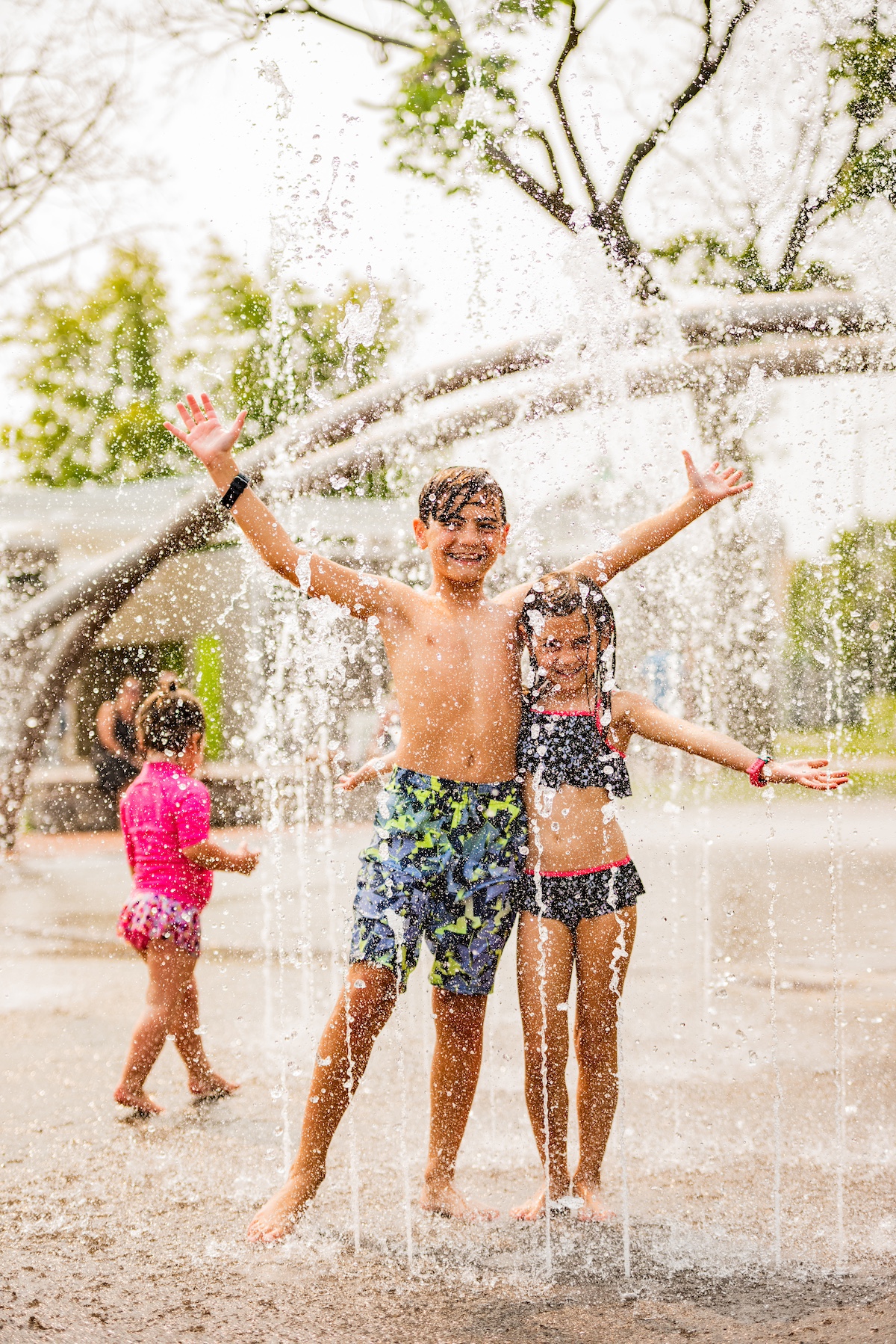 Kids laughing and playing in the splash pad fountains at Clinch Park Beach in Traverse City, a top summer spot for family-friendly outdoor fun.