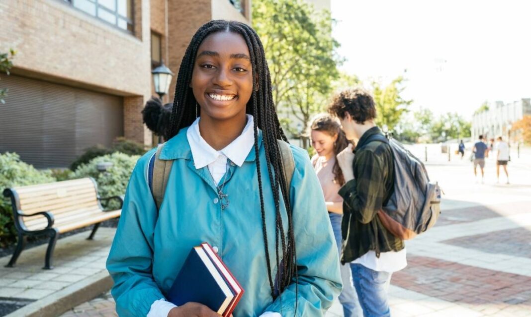 Student smiling on a high school campus while holding books, representing best high schools in Wayne County and strong academic programs.