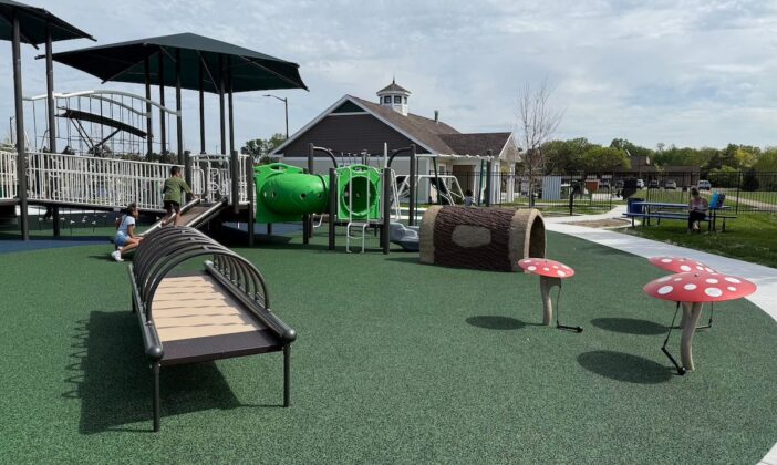 Children playing at Clinton Township inclusive playground featuring a sensory path, whimsical mushroom steppers, accessible climbing tunnels, and a large adaptive play structure.