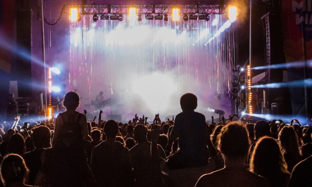 Crowd enjoying a nighttime concert at Middle Waves Music Festival with kids on shoulders during one of the summer festivals in Fort Wayne, Indiana