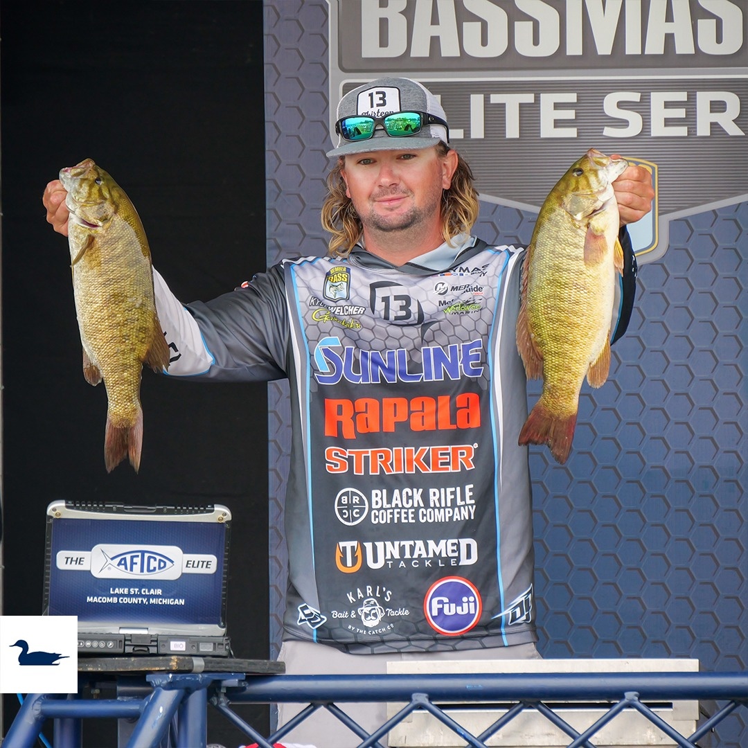 Professional angler at Bassmaster Elite Tournament in Chesterfield holding two bass during weigh-in at Lake St. Clair.