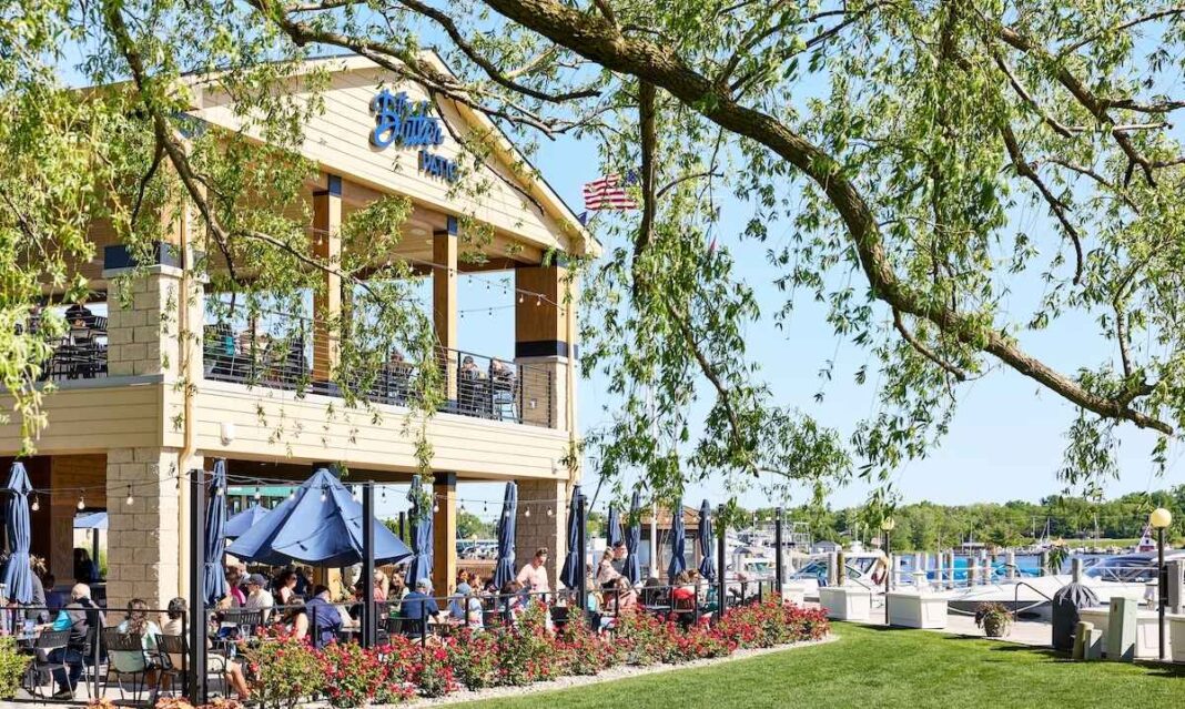 Families dining outdoors at one of the best family restaurants in Saugatuck Michigan, featuring marina views, shaded patio seating, and a scenic waterfront atmosphere.