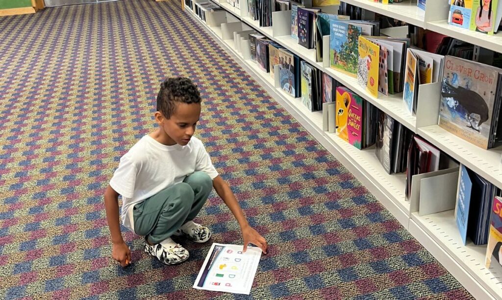 Child participating in a book scavenger hunt at Clinton-Macomb Public Library — one of the best libraries in Macomb County for fun, educational activities for kids.