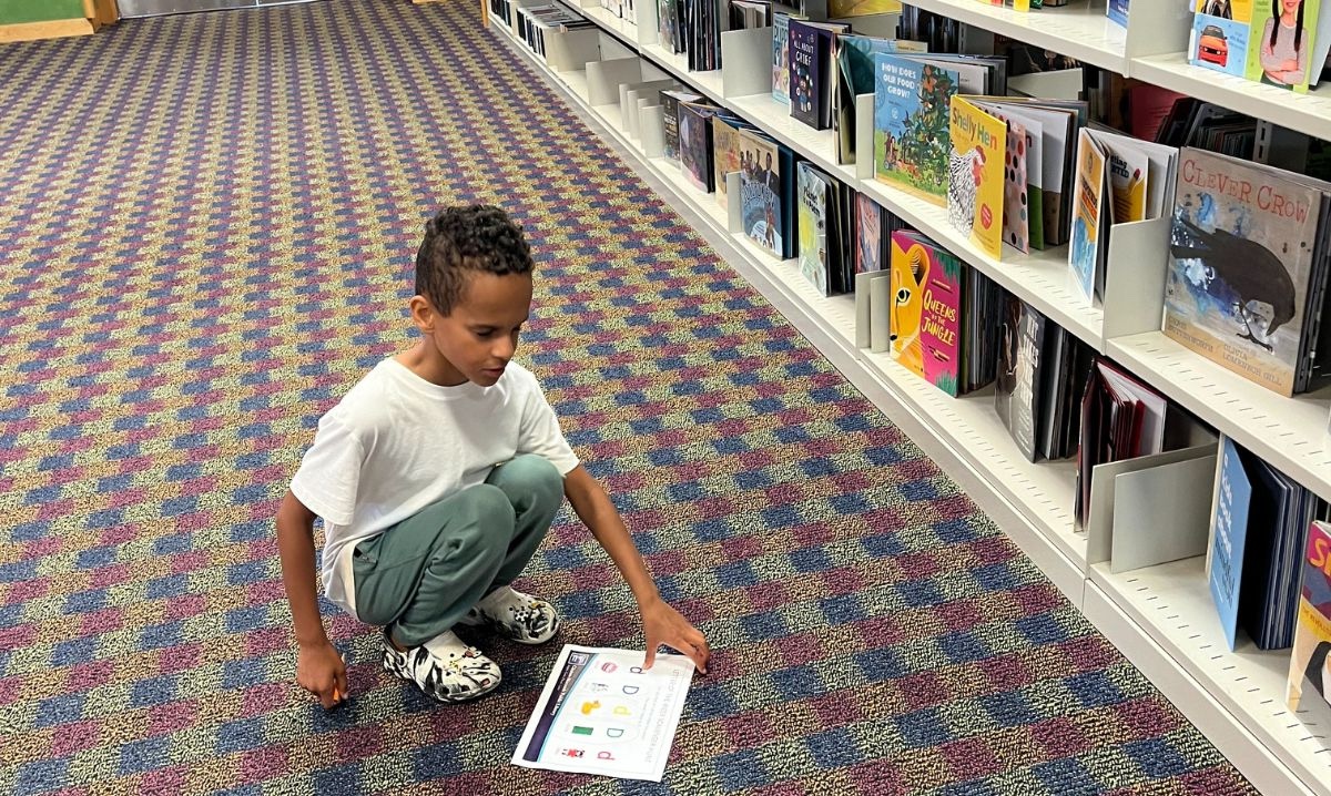 Child participating in a book scavenger hunt at Clinton-Macomb Public Library — one of the best libraries in Macomb County for fun, educational activities for kids.