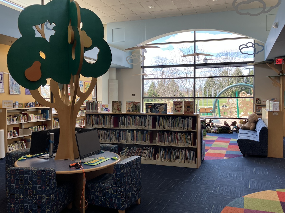 Colorful children’s section at Romeo Graubner Library in Macomb County, featuring reading nooks, kids’ computers, and a view of the outdoor play area — one of the best libraries in Macomb County for families.